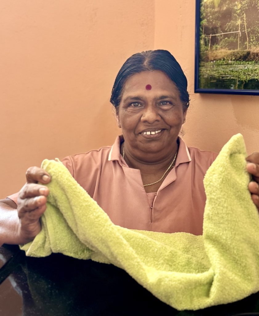 Sati - Massage Therapist at Prakruthi Ayurveda, Cherai Beach, holds a green towel for the steam bath